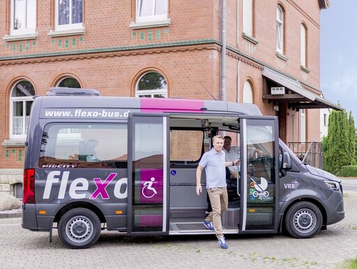 Ein Mann steigt aus einem flexo Bus aus.